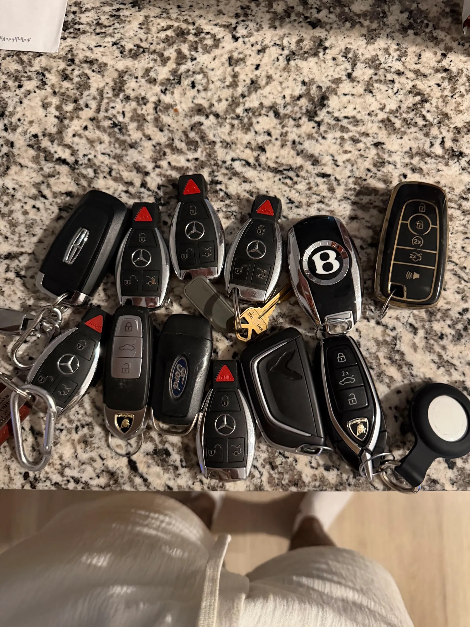 A collection of luxury vehicle keys arranged on a stone surface